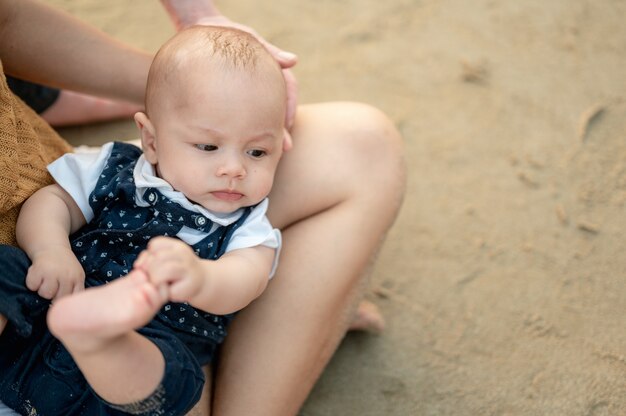 Ujęcie rodziców na plaży trzymającej córeczkę i patrząc na morze. Szczęśliwa rodzina o zachodzie słońca. Rodzina wakacje na plaży latem, koncepcja podróży, wakacji i stylu życia