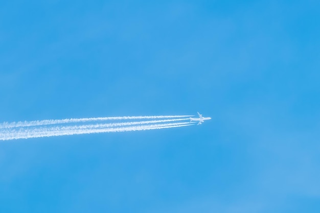 Ujęcie samolotu odrzutowego wysoko na błękitnym niebie Samolot pasażerski na błękitnym niebie pozostawia ślady powietrza Podróżowanie samolotami