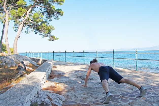 Ujęcie sportowca robi pompki na zewnątrz w pobliżu morza