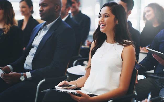 Ujęcie szczęśliwej młodej bizneswoman siedzącej na audytorium konferencji biznesowej