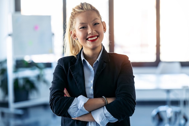 Ujęcie uśmiechnięta młoda bizneswoman patrząc na kamery stojąc w przestrzeni coworkingowej.