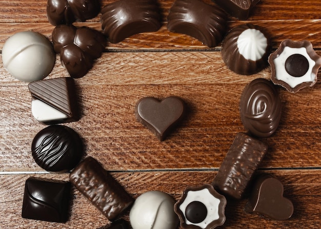 Ujęcie z góry czekoladowego cukierka w kształcie serca otoczonego kilkoma cukierkami Przestrzeń kopiowania Międzynarodowego Dnia Czekolady
