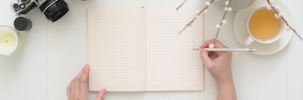 Ujęcie z góry kobiety piszącej na pustym pamiętniku notebooka na stole deski