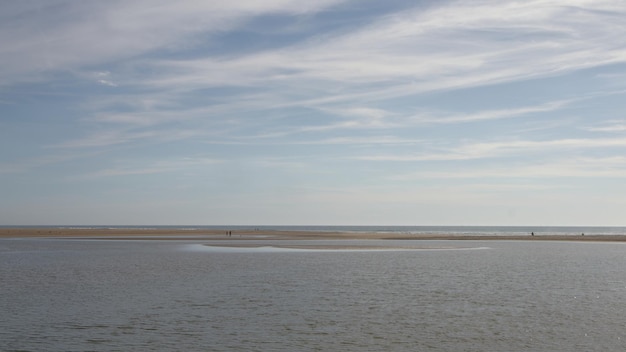 Zdjęcie ujście rzeki i kilka osób na piasku na pierwszym planie