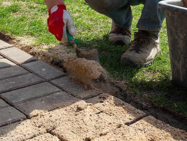 Układanie szarych betonowych płyt chodnikowych w patio na podjeździe na dziedzińcu domu Profesjonalny pracownik