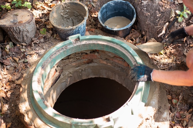 Zdjęcie układanie włazu na studni kanalizacyjnej. mężczyzna wzmacnia szyję szamba.