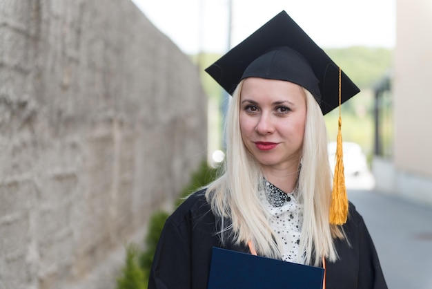 Zdjęcie ukończona dziewczyna trzymająca dyplom z dumą