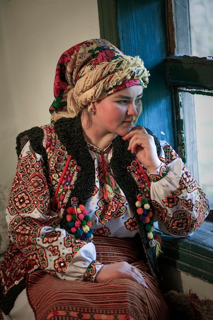 Ukraińska huculska kobieta w stroju ludowym siedzi przy oknie. Wszystko będzie Ukrainą.