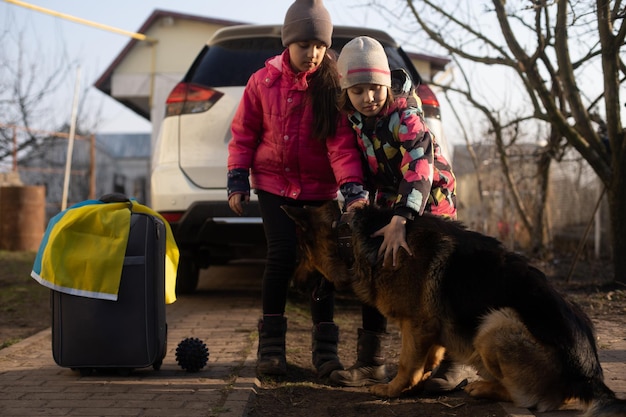 Ukraińska migracja wojskowa. dwie małe dziewczynki z walizką. Flaga Ukrainy, pomoc. Kryzys, konflikt zbrojny