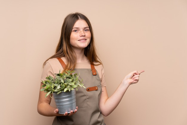 Ukraińska nastolatka ogrodnik dziewczyna trzyma roślinę palcem wskazującym na bok