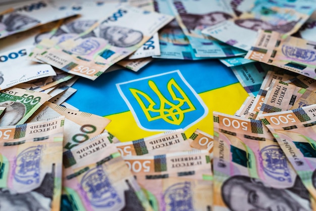 Ukraińska waluta hrywna na tle ukraińskiej flagi Pomoc państwa dla obywateli w związku z wojną na Ukrainie