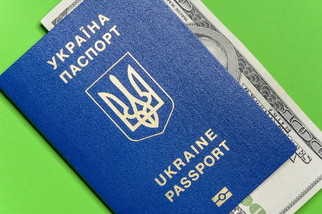 Ukraiński paszport biometryczny ze studolarowym banknotem na zielonym tle