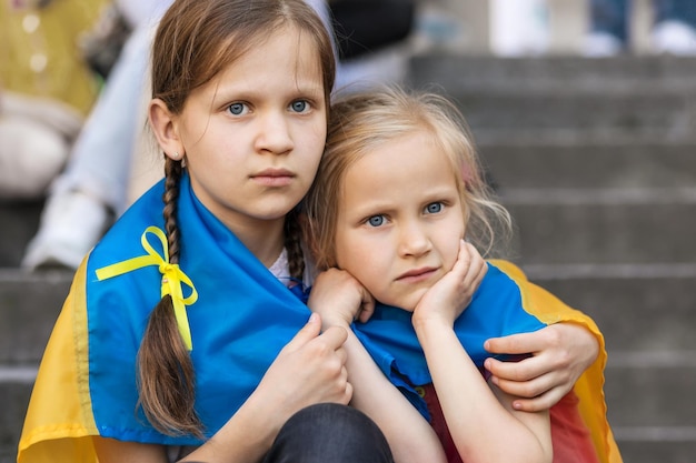 Ukraińskie dzieci Uchodźca Smutne migrujące dzieci Dzieci z ewakuacji owinięte flagą Ukrainy podczas rajdu