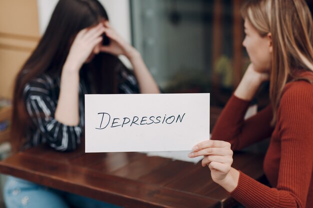 Ukryta koncepcja depresji i zdrowia psychicznego. Smutna kobieta z psychologiem trzyma w ręku białą kartkę papieru z napisem Depresja.