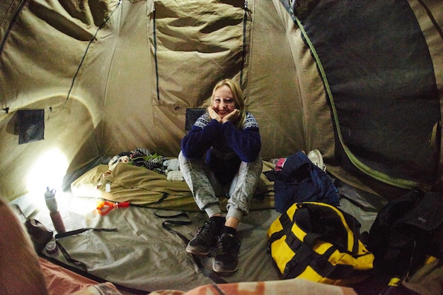 Ukrywanie się w obozie Ujęcie uśmiechniętej kobiety siedzącej w nocy w namiocie