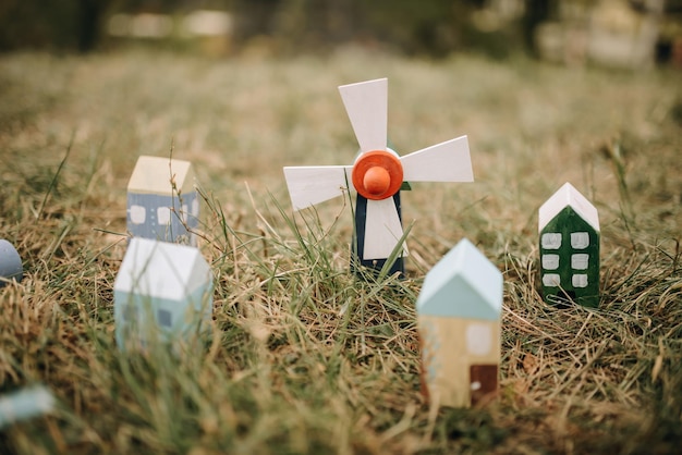 Ulica z drewnianymi domkami zabawkowymi i wiatrakami na trawie Małe domy z zabawkami Młyn