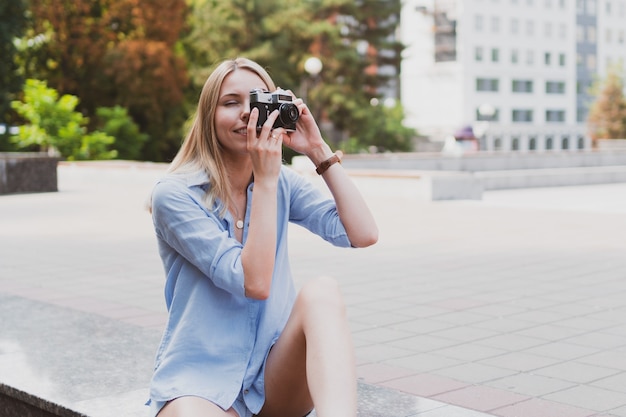 Uliczny portret młodej uroczej kobiety trzymającej aparat retro