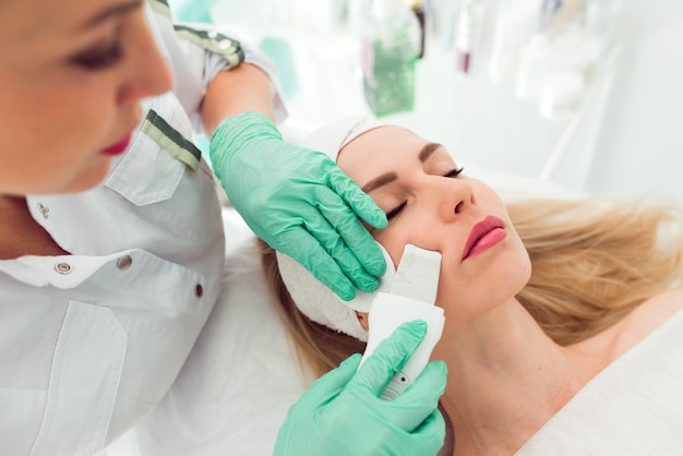 Ultradźwiękowy skruber kosmetyczny Procedura kawitacji twarzy Młoda kobieta klient klinika urody uzyskać pro