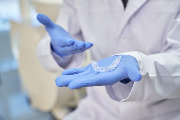 Umiejętny dentysta prezentujący silikonową formę zębów