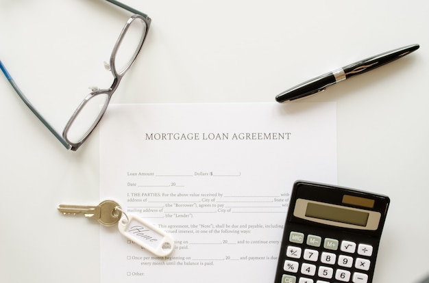 Zdjęcie umowa o kredyt hipoteczny, koncepcja z kalkulatorem, klucze i długopis na formularzu lub umowie o kredyt hipoteczny. widok z góry.
