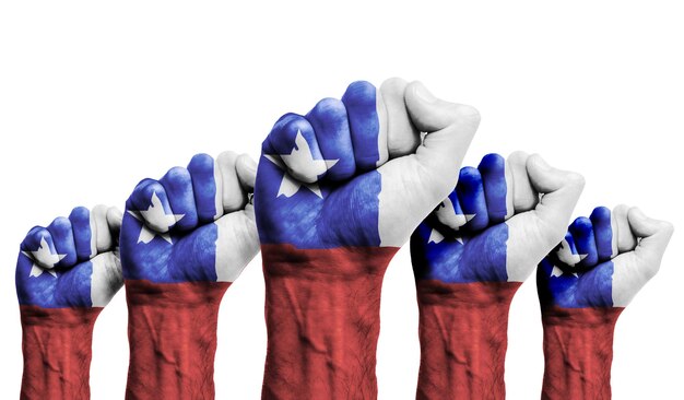 Uniesiona pięść protestujących z namalowaną flagą Chile