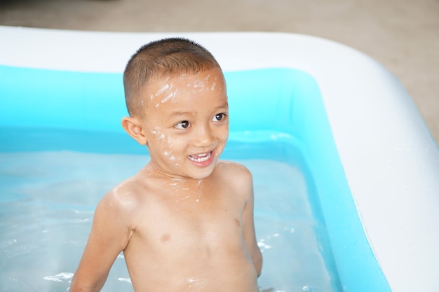 Upalna pogoda Chłopiec szczęśliwie bawi się wodą w wannie