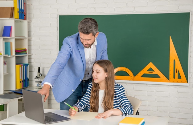 Uradowane dziecko z nauczycielem w klasie korzysta z laptopa