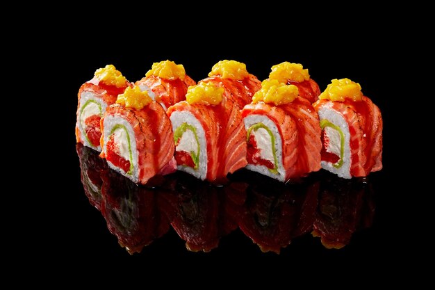 Uramaki roll z serkiem tobiko awokado smażony łosoś mango na czarnym tle