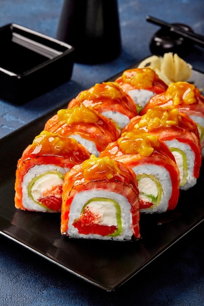 Uramaki roll z serkiem tobiko awokado smażony łosoś mango podawany z sosem sojowym