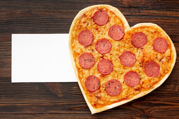 Zdjęcie urocza aranżacja na kolację walentynkową z pizzą i kartą w kształcie serca
