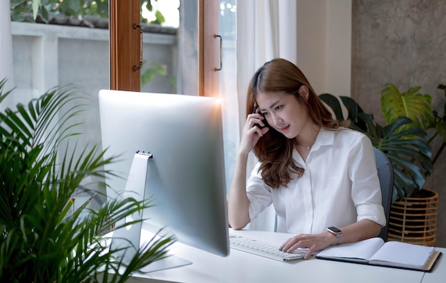 Urocza azjatycka bizneswoman siedząca pracująca na laptopie w biurze