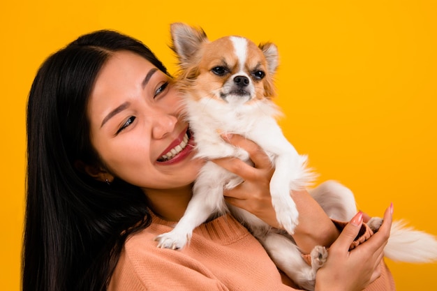 Urocza azjatycka kobieta ze swoim miłośnikiem psów chihuahua chihuahua Szczęście dziewczyny, która kocha swojego psa Miłość do ludzi i uroczych psów sesja zdjęciowa w pomarańczowym studio