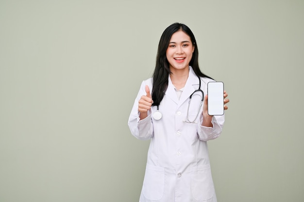 Urocza azjatycka lekarka pokazująca kciuk w górę, trzymająca makietę smartfona