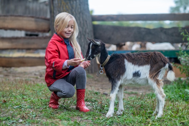 Urocza blondynka bawi się kozą na farmie