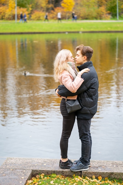 Urocza brunetka facet i ładna blondynka na randkę. Kochający nastolatkowie są szczęśliwi, uśmiechnięci, całują się.