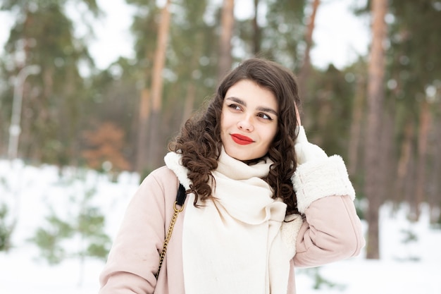 Urocza brunetka z długimi włosami nosi płaszcz w zimie