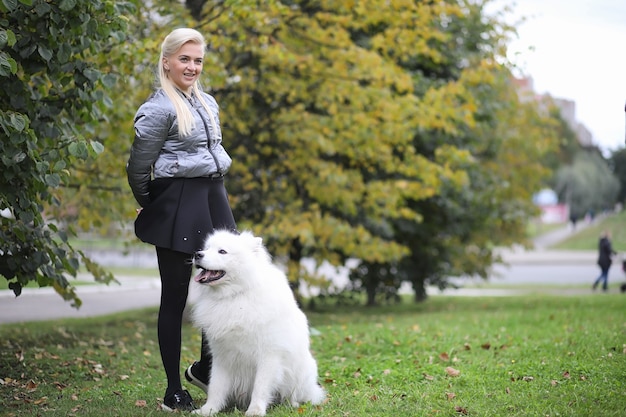 Urocza dziewczyna na spacerze z pięknym puszystym psem Samoyed