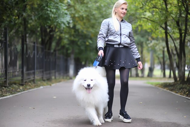Urocza dziewczyna na spacerze z pięknym puszystym psem Samoyed