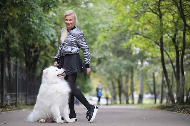 Urocza dziewczyna na spacerze z pięknym puszystym psem Samoyed