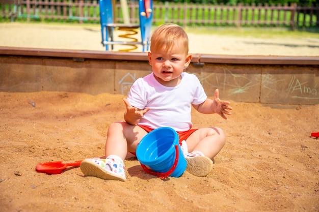 Urocza dziewczynka bawi się piaskiem na piaskownicy na placu zabaw