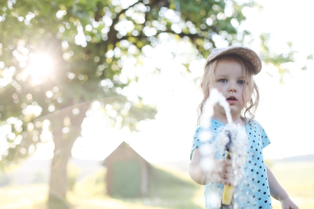 Urocza dziewczynka bawi się wężem ogrodowym w upalny i słoneczny letni dzień