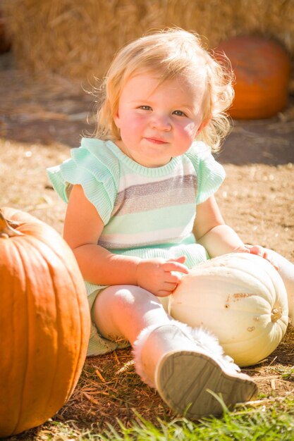 Urocza dziewczynka bawiąca się na rustykalnym ranczu na Pumpkin Patch