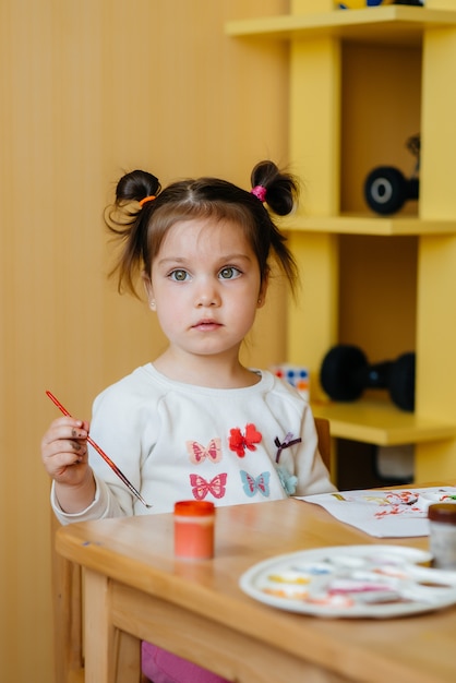 Urocza mała dziewczynka bawi się i maluje w swoim pokoju. Rekreacja i rozrywka.