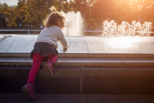 Urocza mała dziewczynka bawi się w słoneczny, piękny dzień w parku