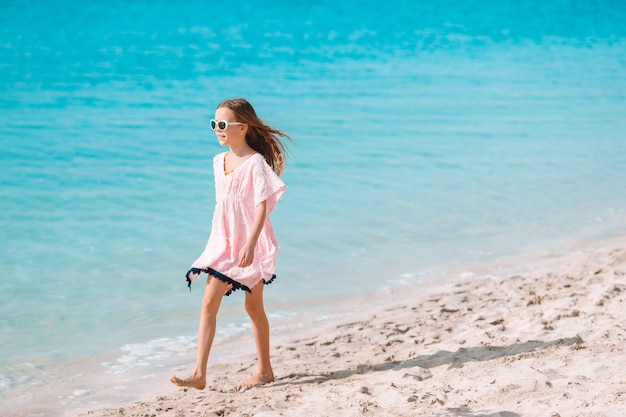 Urocza mała dziewczynka bawić się na tropikalnej plaży podczas wakacji