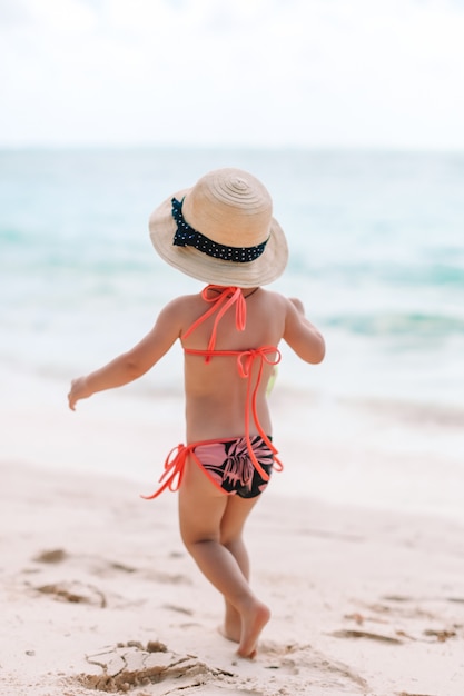 Urocza mała dziewczynka bawić się na tropikalnej plaży podczas wakacji