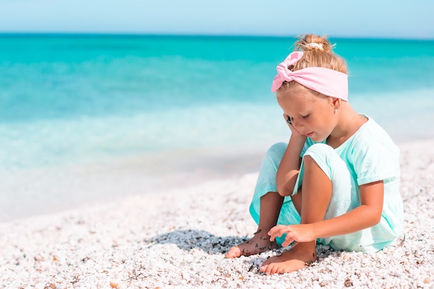 urocza mała dziewczynka bawić się z piaskiem na plaży