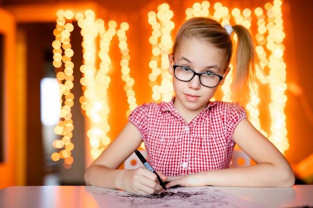 Urocza mała dziewczynka pisze list do Santa Klaus siedzącego na stole
