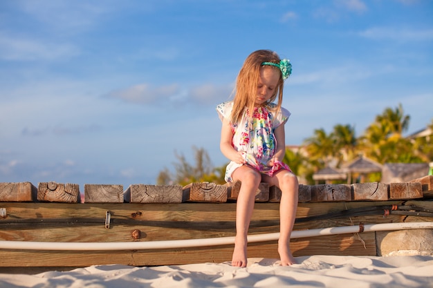 Urocza mała dziewczynka przy białą tropikalną plażą w zmierzchu