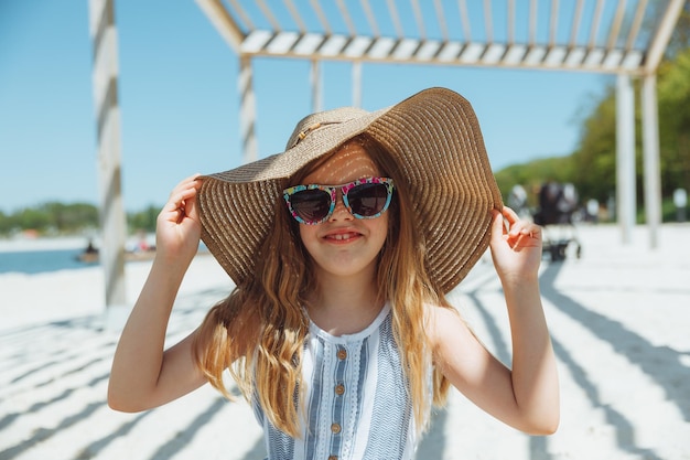 Urocza mała dziewczynka w kapeluszu na plaży na letnie wakacje